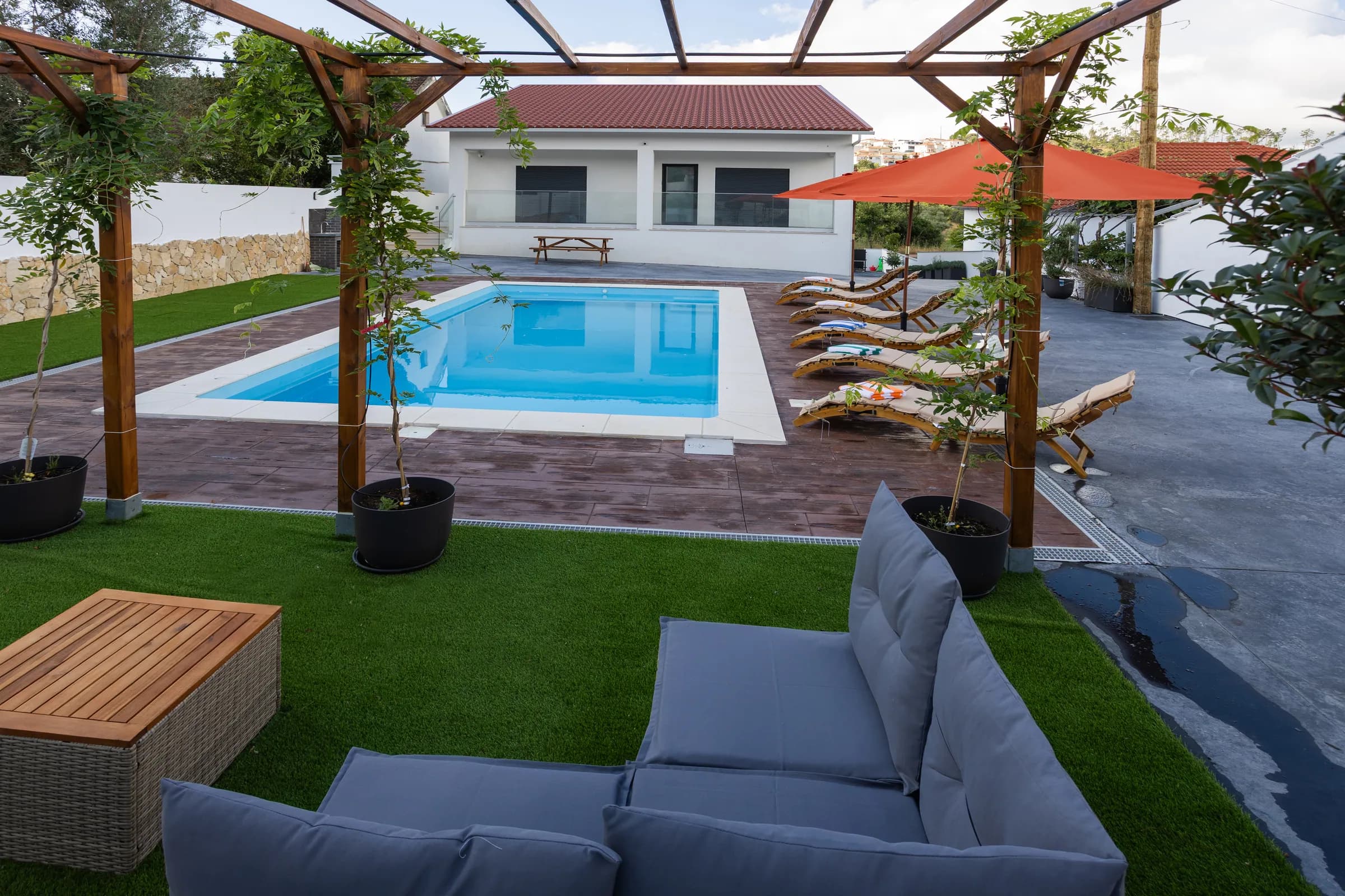 Shaded pergola lounge with outdoor sofas facing the pool